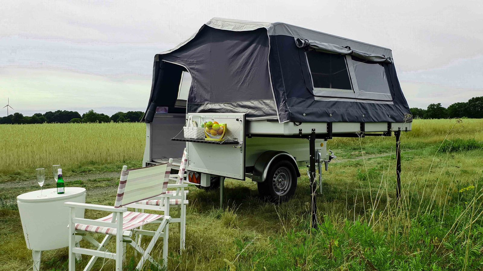 Klappcamper Seitenansicht mit Blick auf den umgeklappten Deckel und aufgebautem Zelt