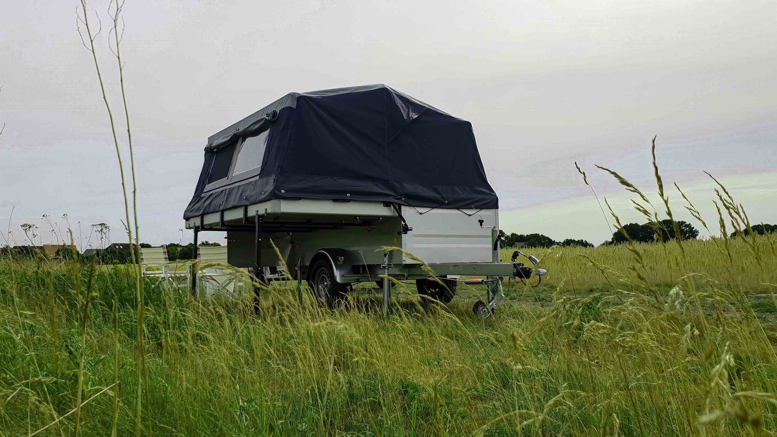Sicht auf die Vorderseite des Campinganhängers mit aufgestelltem Zelt in der Natur