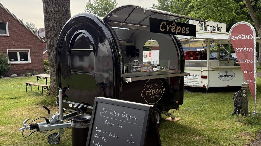 Schwarzer Foodtrailer als Crêperie vor einem Backsteinhaus